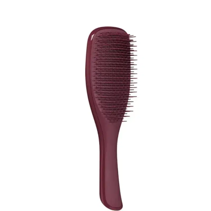 A imagem mostra uma escova de cabelo na cor vinho, com corpo plástico alongado com formato ergonômico, compacto e portátil e cerdas também de plástico.