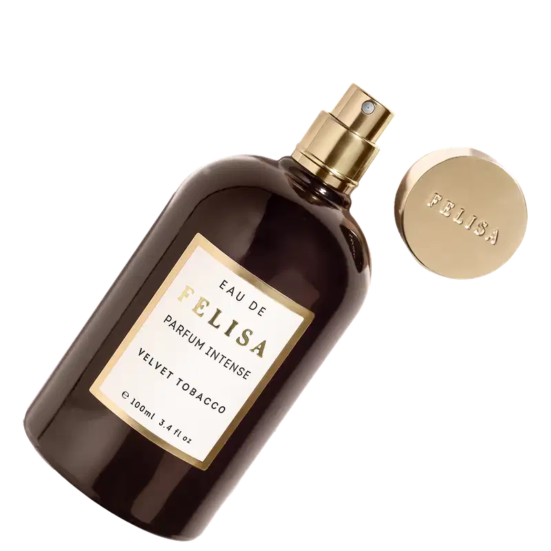 Perfume Felisa em frasco de vidro âmbar com detalhes dourados. Frasco retangular de 100ml com tampa dourada. Rótulo branco com texto "Eau de Felisa Parfum Intense Velvet Tobacco". Embalagem com o nome "Felisa" em relevo dourado na parte inferior.
