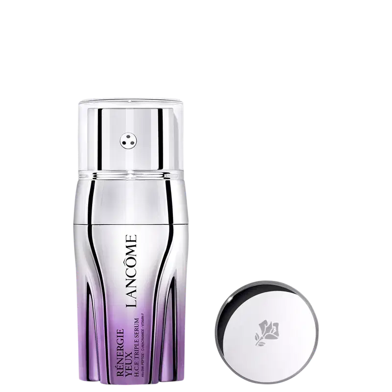 Sérum em frasco cilíndrico com degradê de roxo na base. O frasco tem tampa prateada com pequeno orifício central. Ao lado, tampa prateada redonda com logotipo floral gravado. Embalagem minimalista com nome do produto e marca visíveis no frasco.