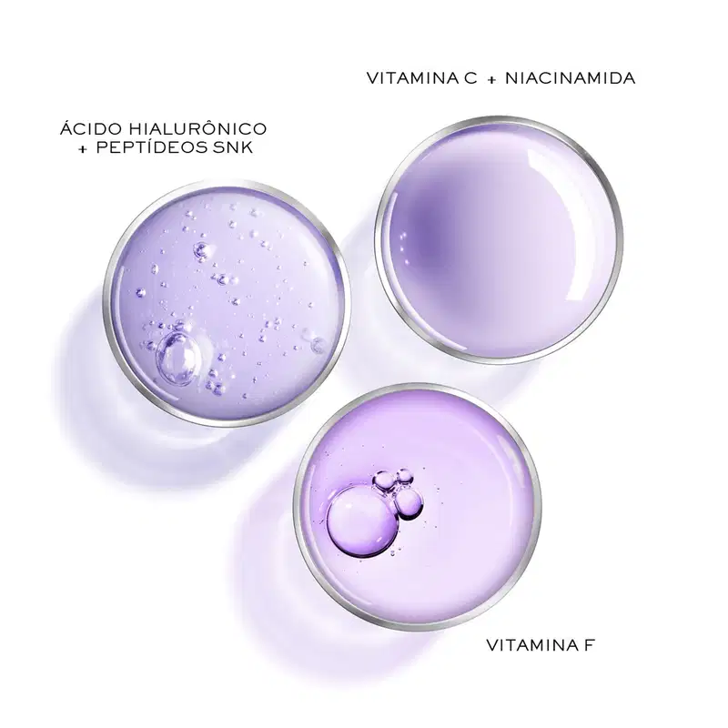 Três frascos de vidro transparente com formatos arredondados contendo líquidos de cor lilás e bolhas visíveis dentro dos líquidos.  Abaixo há textos descrevendo os ingredientes: Vitamina C + Niacinamida, Ácido Hialurônico + Peptídeos SNK e Vitamina E.