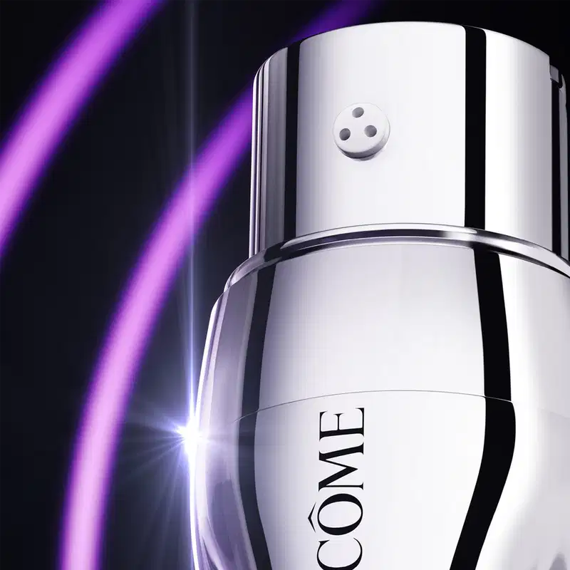 Sérum em frasco cilíndrico branco e cromado. Tem tampa arredondada com três pequenos círculos. Na parte inferior, está impresso o logotipo "CÔNE", pedaço do nome da marca Lancôme. O frasco está posicionado contra um fundo preto, com um feixe de luz roxa.
