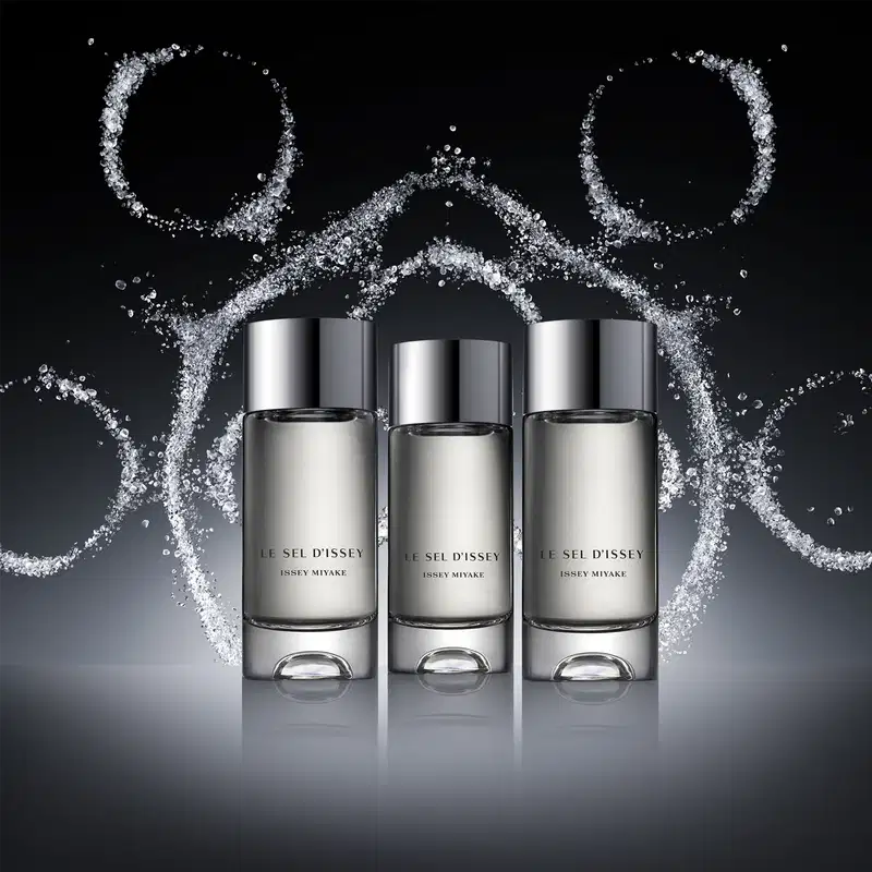 3 frascos de perfumes de diferentes tamanhos. Ao fundo, há um efeito de respingos e partículas que criam um visual dinâmico e sugestivo.