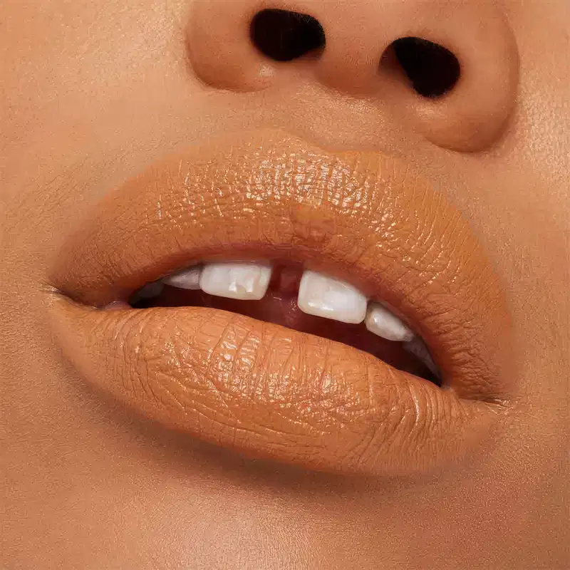 A imagem mostra a boca de uma mulher usando o batom.