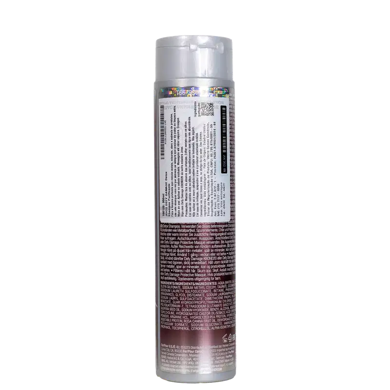 Frasco cilíndrico branco de plástico para shampoo da marca Joico. O rótulo contém informações detalhadas sobre o produto, incluindo ingredientes e instruções, em várias línguas. O frasco tem tampa prata e apresenta as cores branca e roxa.