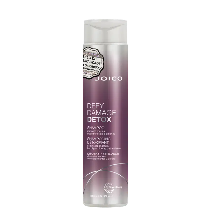 Shampoo detox Defy Damage da marca Joico. Embalagem cilíndrica roxa com detalhes prateados. Rótulo indicando que remove metais, minerais traço e cloro dos cabelos. Volume de 10.1 fl oz / 300ml.