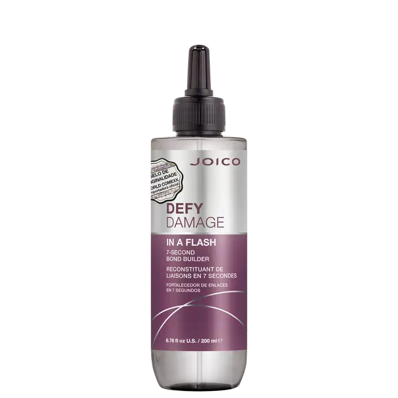 É um produto de tratamento capilar da marca Joico. A embalagem é um frasco que tem um aplicador preto na parte superior. O rótulo na frente é predominantemente branco e roxo. O nome do produto "Defy Damage In a Flash" está escrito em letras grandes;