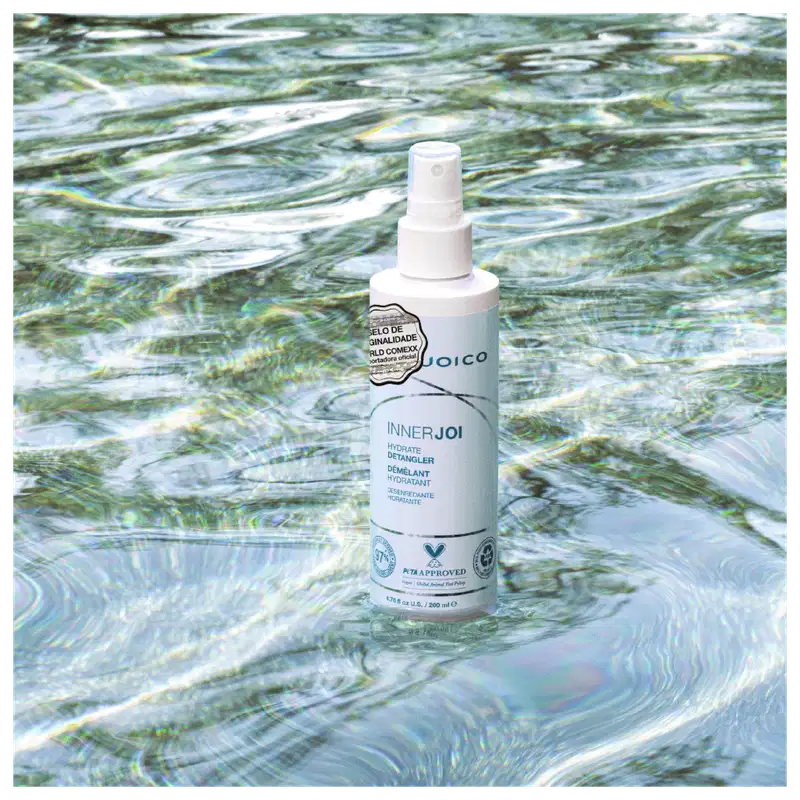 O Leave-in Joico InnerJoi Hydrate Detangler (200ml), em sua embalagem verde com detalhes em branco, se destaca em um fundo que lembra água cristalina, transmitindo uma sensação de leveza e frescor