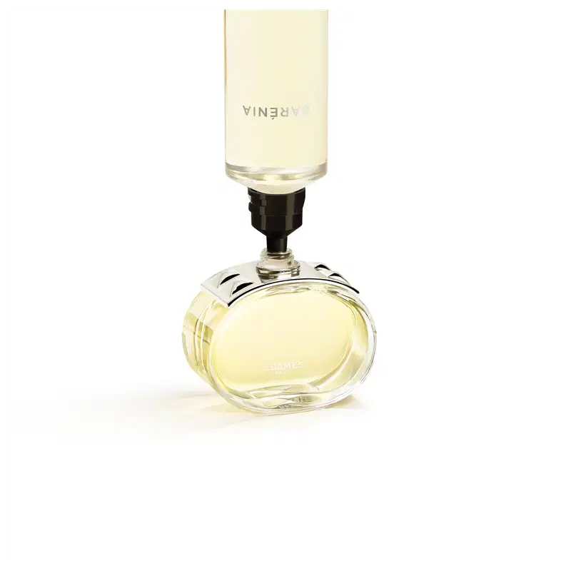 Perfume em frasco de vidro transparente com detalhes cromados sendo preenchido pelo seu refil.