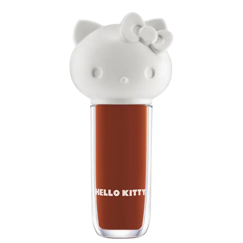 Maquiagem em formato cilíndrico com a cabeça da personagem Hello Kitty como tampa. A parte superior é branca com detalhes em relevo que representam os olhos, orelhas e laço da Hello Kitty. É possível ver a cor do produto pelo corpo transparente.