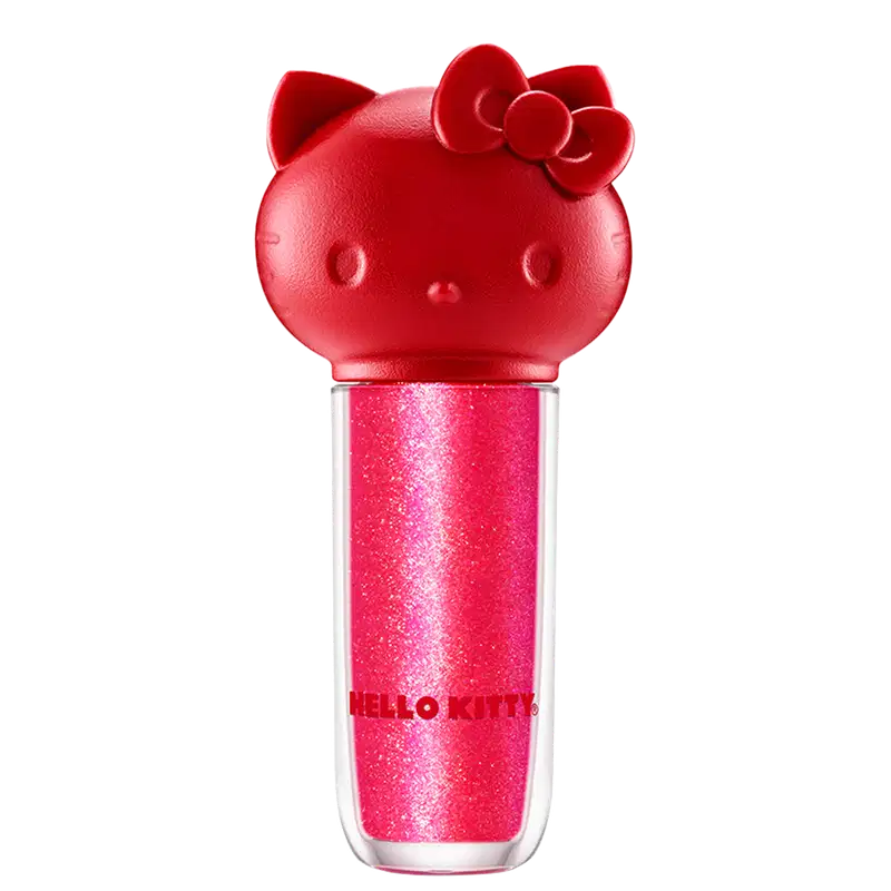 Maquiagem em formato cilíndrico com a cabeça da personagem Hello Kitty como tampa. A parte superior é vermelha com detalhes em relevo que representam os olhos, orelhas e laço da Hello Kitty. É possível ver a cor do produto pelo corpo transparente.