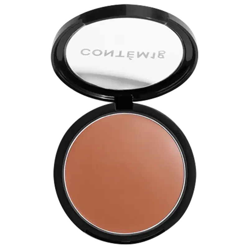 A imagem mostra uma embalagem aberta de bronzer cremoso. A embalagem é preta com parte transparente e o logo da marca em branco.