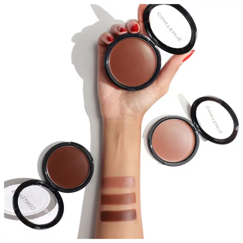 A imagem mostra um antebraço com as três opções de cores disponíveis do bronzer, além dos três produtos abertos perto do braço.