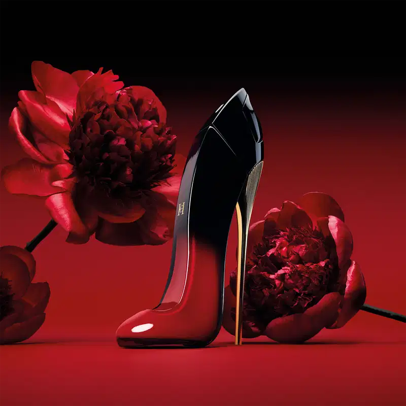 Frasco do perfume cercado por flores vermelhas em um fundo vermelho.