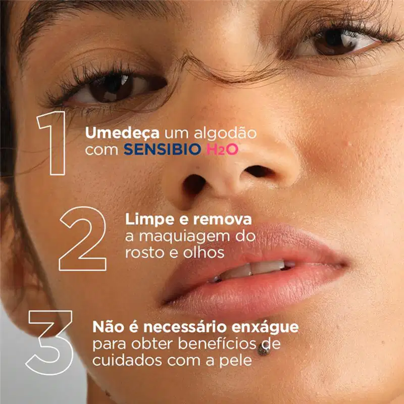Uma mulher com olhos castanhos e cílios longos usa um algodão com Sensibio H2O, um produto de limpeza de rosto e olhos da marca Bioderma.
