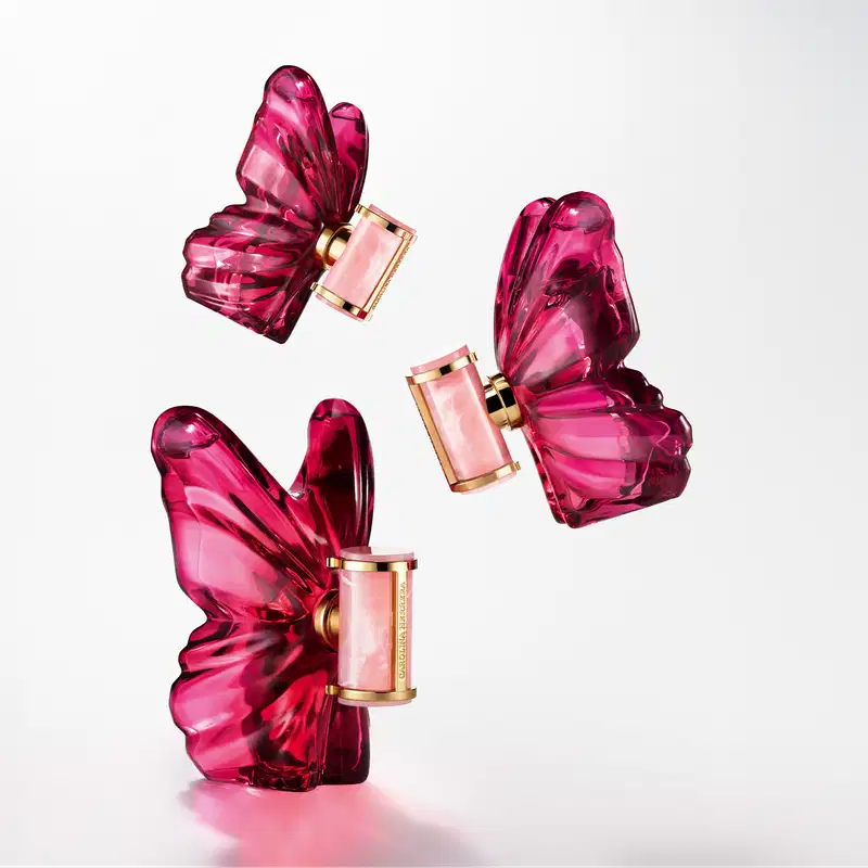 Frasco de perfume Carolina Herrera em formato de borboleta, com tampa dourada e corpo em tom de rosa intenso, destacando a elegância e sofisticação da marca.