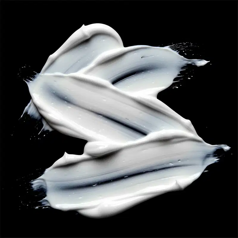 Imagem de um produto de beleza com textura cremosa e brilhante, em tons de branco e preto, sugerindo um ambiente sofisticado e elegante para aplicação do produto.