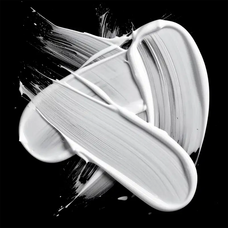 A imagem mostra uma textura cremosa e brilhante de um produto de beleza, com tons de branco e preto contrastantes. A consistência parece ser suave e sedosa, com linhas e ondulações que sugerem uma aplicação fluida e uniforme.
