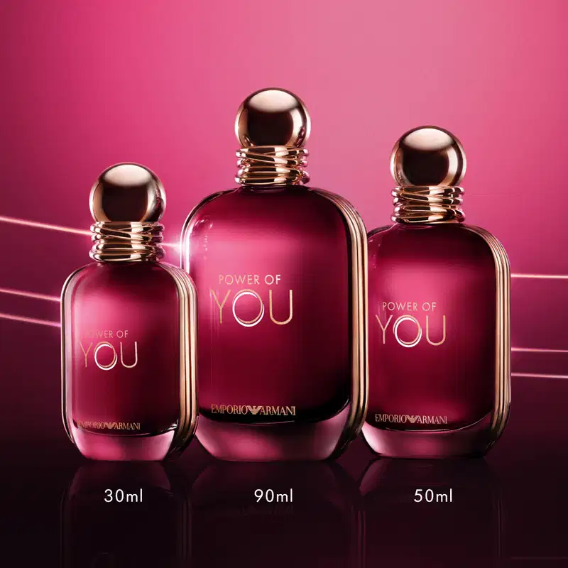Três frascos de perfume da linha "Power of You" da Emporio Armani, em diferentes tamanhos (30ml, 50ml e 90ml), com embalagens em tom de rosa vibrante e detalhes em dourado.
