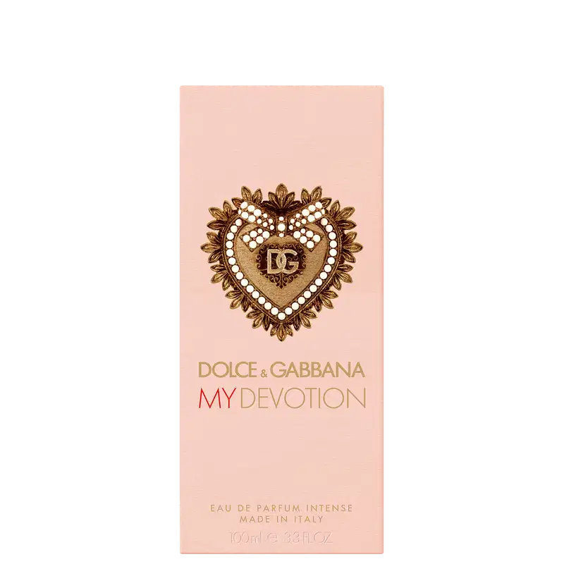 Caixa de item de perfumaria com tampa dourada em formato de coração ornamentado. Embalagem rosa clara com detalhes dourados. 
