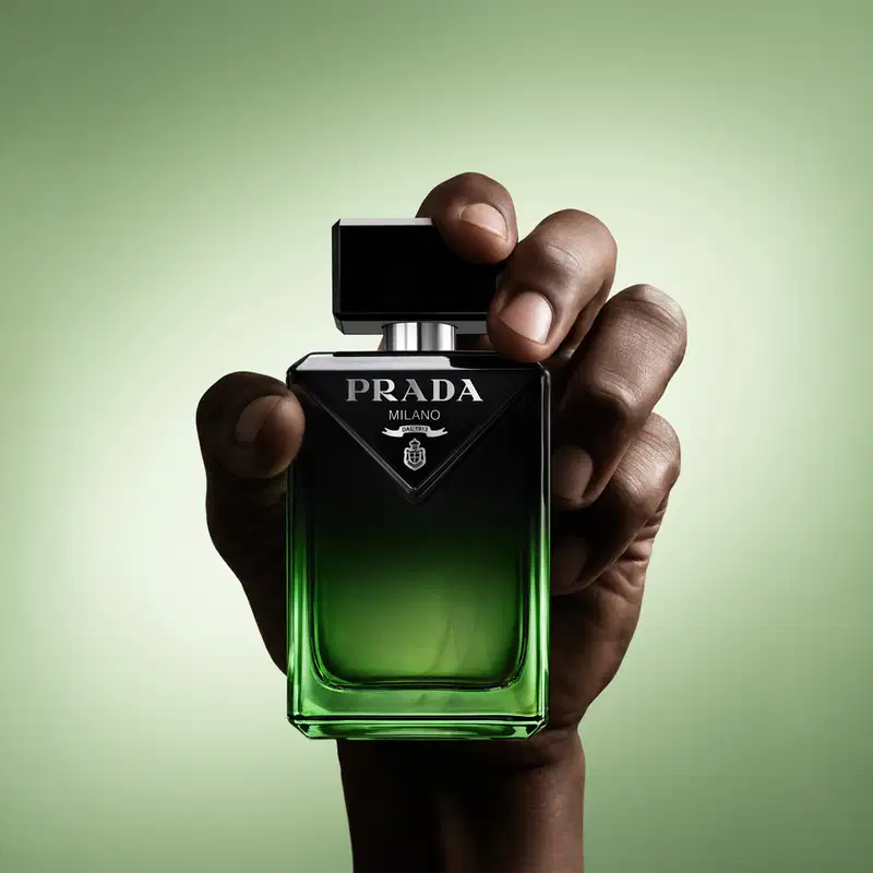 Frasco de perfume Prada Milano com design preto e verde, exibindo o logotipo da marca em destaque. O recipiente possui formato retangular com tampa preta e apresenta uma cor verde vibrante na parte inferior.