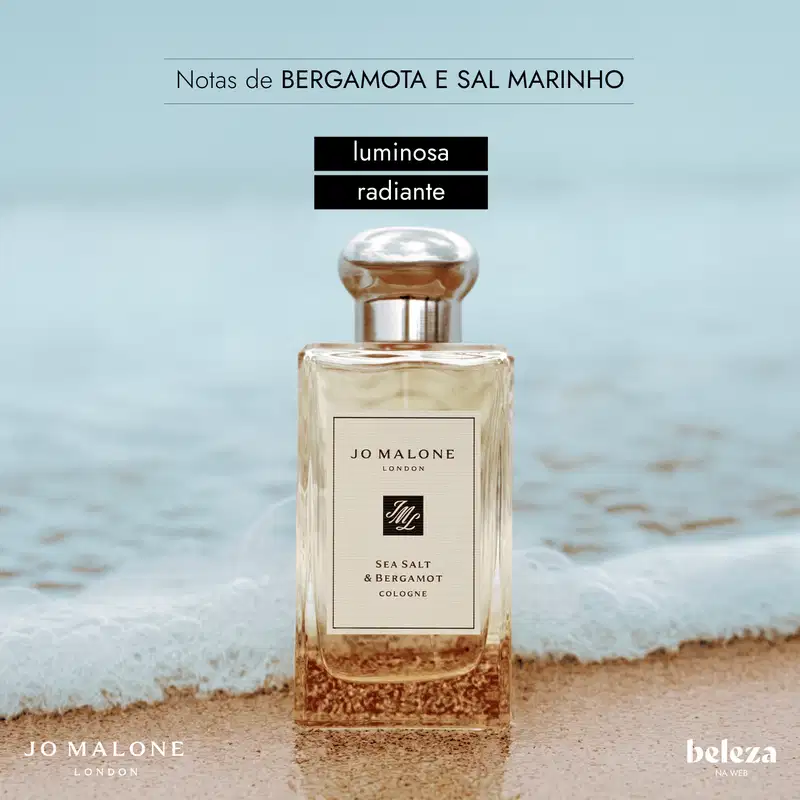 Frasco de item de perfumaria da marca Jo Malone London com rótulo "Sea Salt & Bergamot Cologne" em fundo de praia arenosa e água.