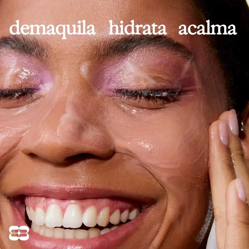 Rosto feminino com pele brilhante e expressão de satisfação. Texto legível: "demaquila hidrata acalma".