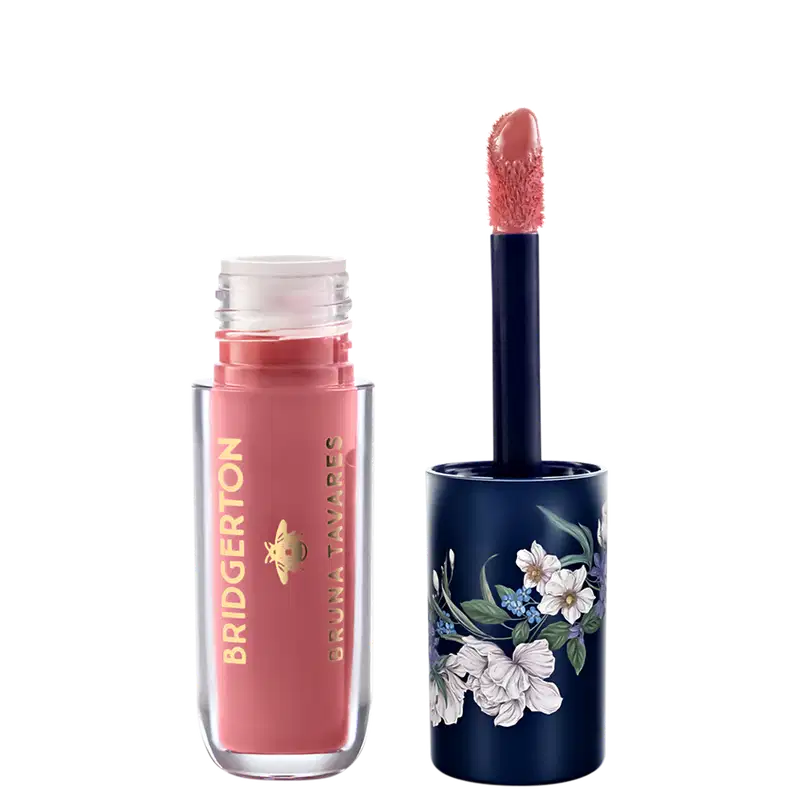 Embalagem de item de maquiagem da marca Bruna Tavares em tom de rosa, com aplicador de espuma, e tampa decorada com flores em fundo azul escuro.