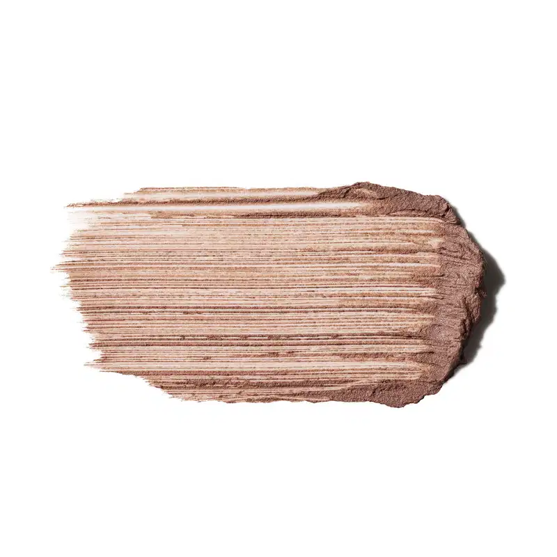 Textura cremosa com acabamento mate e linhas horizontais marcadas. Tons de bege e marrom claro predominam. Consistência densa e pigmentada, com superfície levemente granulada e efeito de pó compactado, típico de produtos de base ou contorno.