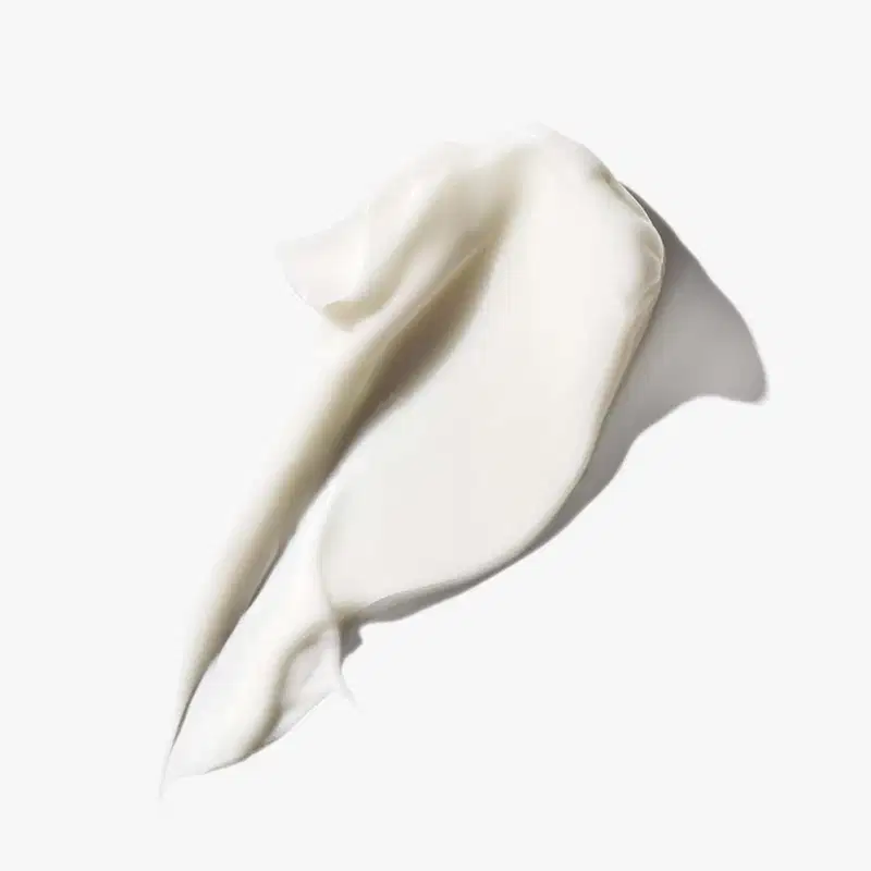 Textura cremosa e suave, com aparência sedosa e brilhante, típica de um produto de cuidados com a pele da marca Clinique. A cor predominante é o branco, transmitindo uma sensação de pureza e delicadeza.
