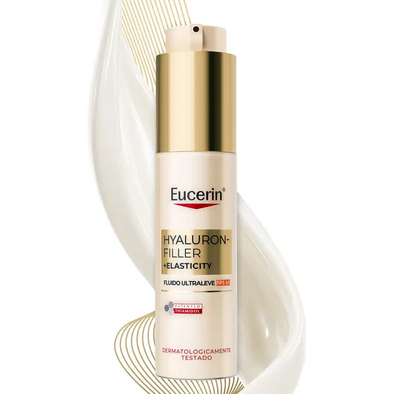Embalagem dourada e branca de um produto de cuidados com a pele da marca Eucerin, com informações sobre seus benefícios de preenchimento e elasticidade, em um ambiente minimalista e iluminado.