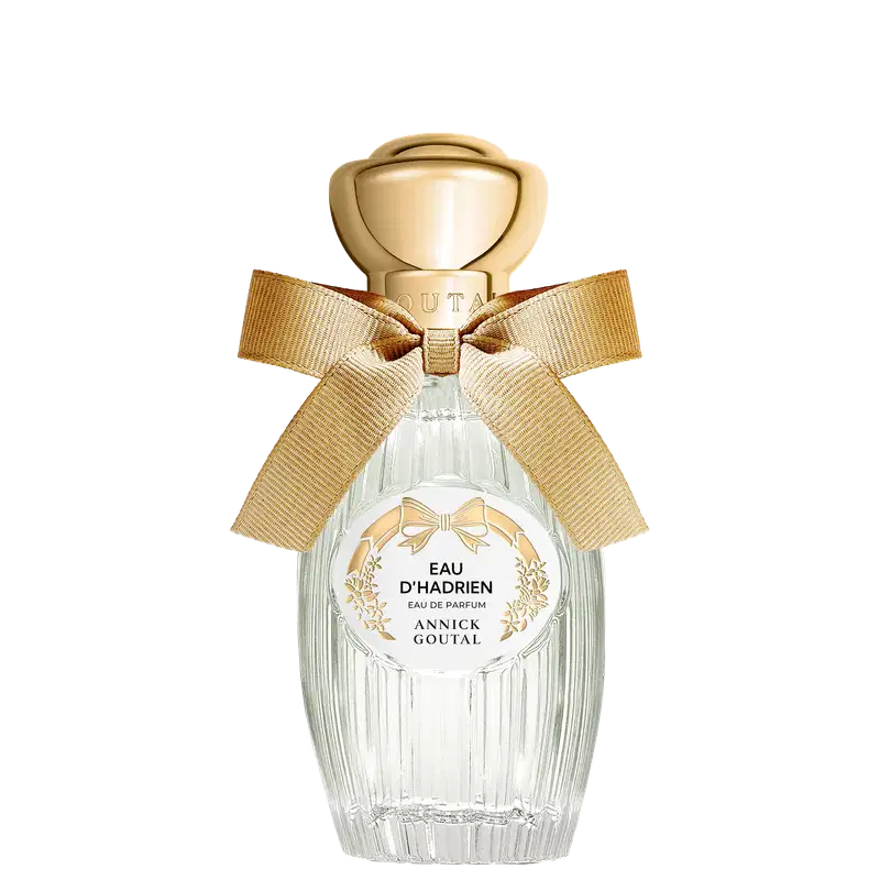 Eau de Parfum Eau d'Hadrien da Annick Goutal em frasco de cristal estriado com tampa dourada em formato de esfera. Decorado com laço de fita bege e rótulo circular branco com detalhes florais dourados.