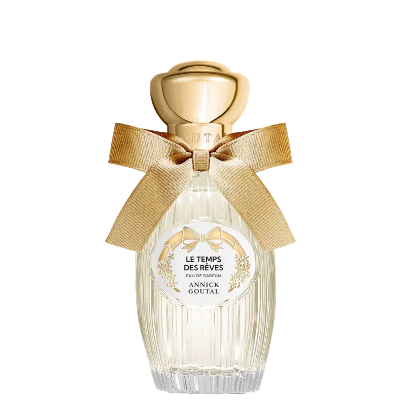 Eau de Parfum "Le Temps des Rêves" Annick Goutal em frasco de cristal transparente com tampa dourada esférica, laço de fita bege e rótulo circular branco com detalhes florais dourados.