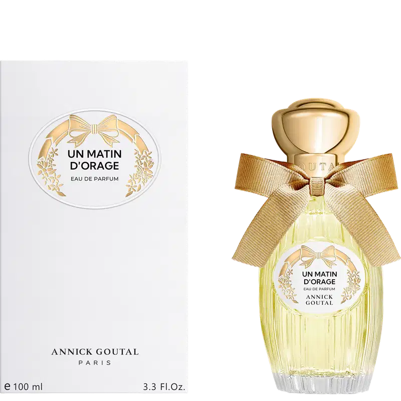 Eau de Parfum "Un Matin d'Orage" da Annick Goutal Paris. Frasco de vidro com 100ml, líquido amarelo claro, tampa dourada esférica, laço bege, rótulo branco com gravura de laço e flores douradas.