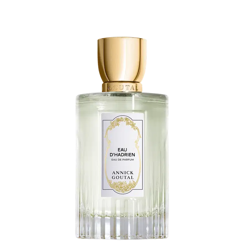Eau de Parfum Eau d'Hadrien da Annick Goutal em frasco cilíndrico de vidro transparente com líquido incolor. Tampa dourada cilíndrica. Rótulo branco com ornamentação dourada e texto em preto.