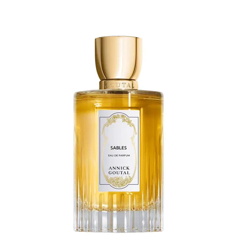 Eau de Parfum Sables da Annick Goutal em frasco cilíndrico de vidro com líquido amarelo dourado. Tampa dourada polida. Rótulo branco com ornamentação dourada e texto em preto. Base estriada em vidro transparente.