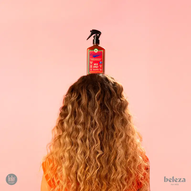 Frasco de spray de leite da marca Lola From Rio, com rótulo rosa e verde destacando a fórmula natural e vegana do produto. O frasco possui um gatilho preto e contém 250 ml do produto.