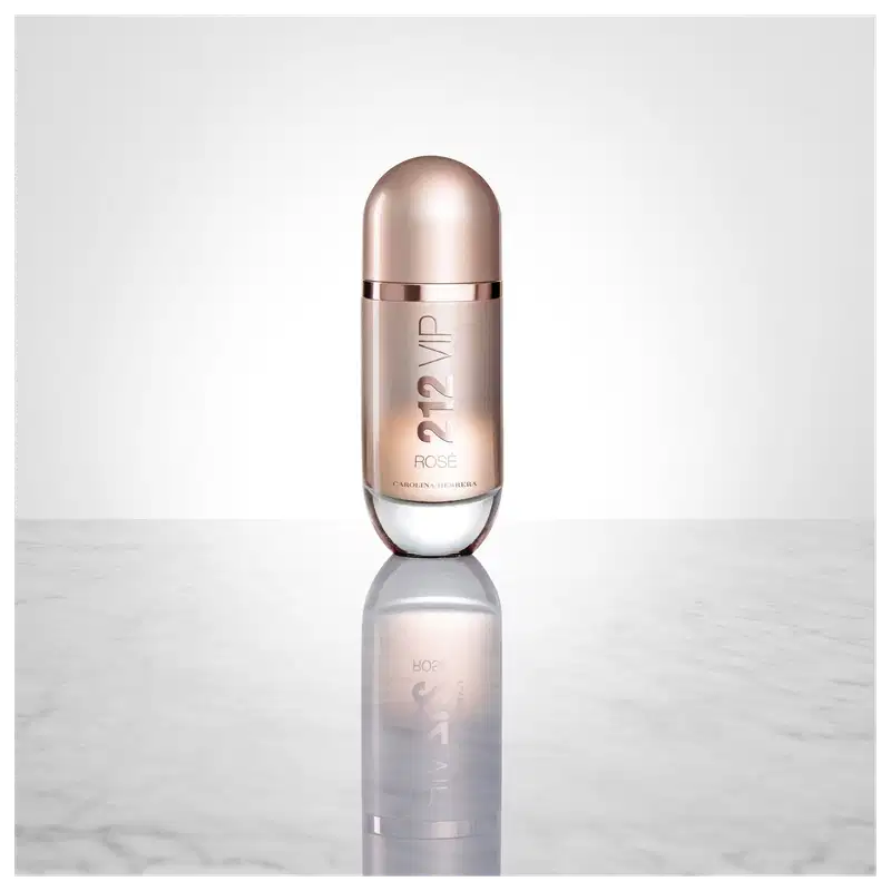 Perfume em frasco cilíndrico de metal rosado. O frasco tem um formato alongado com uma tampa arredondada na parte superior. O rótulo frontal exibe o texto "212 VIP Rosé" em letras douradas sobre fundo rosado.