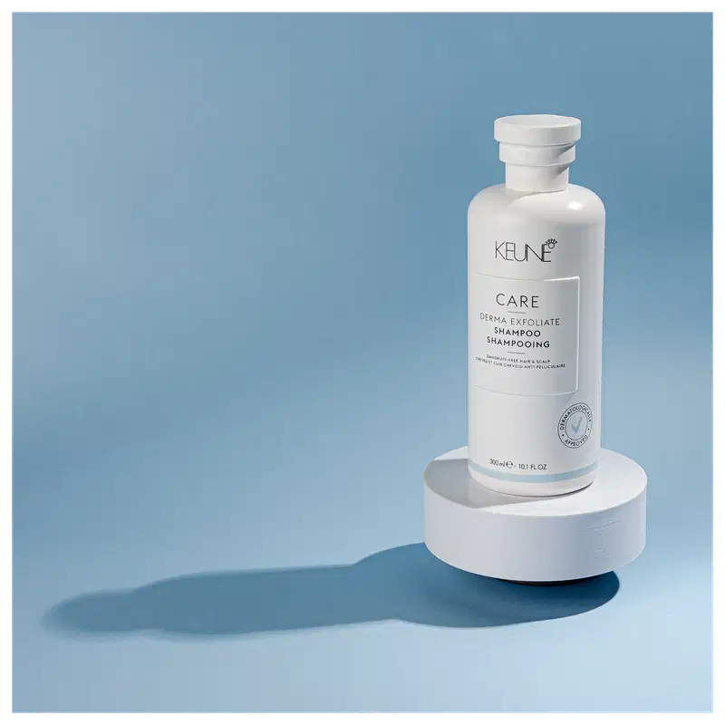 Frasco branco de shampoo Keune Care Derma Exfoliate, com rótulo em preto e branco indicando o nome do produto e sua função de remover caspa do couro cabeludo.