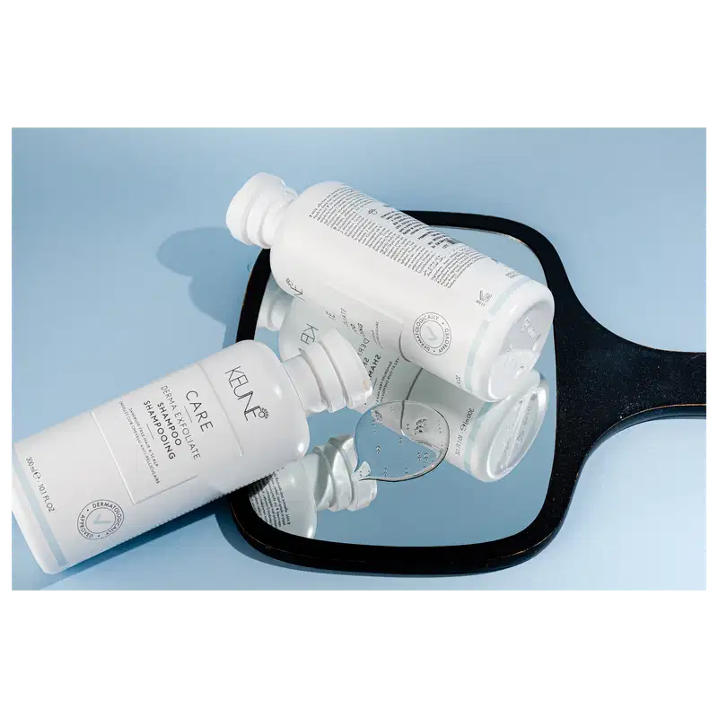Frasco branco de shampoo Keune Care Derma Exfoliate, com rótulo em preto e branco indicando o nome do produto e sua função de remover caspa do couro cabeludo.