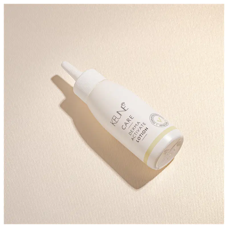 Frasco branco de loção ativadora Keune Care Derma Activate, com rótulo em preto e amarelo, apresentando informações sobre o produto.