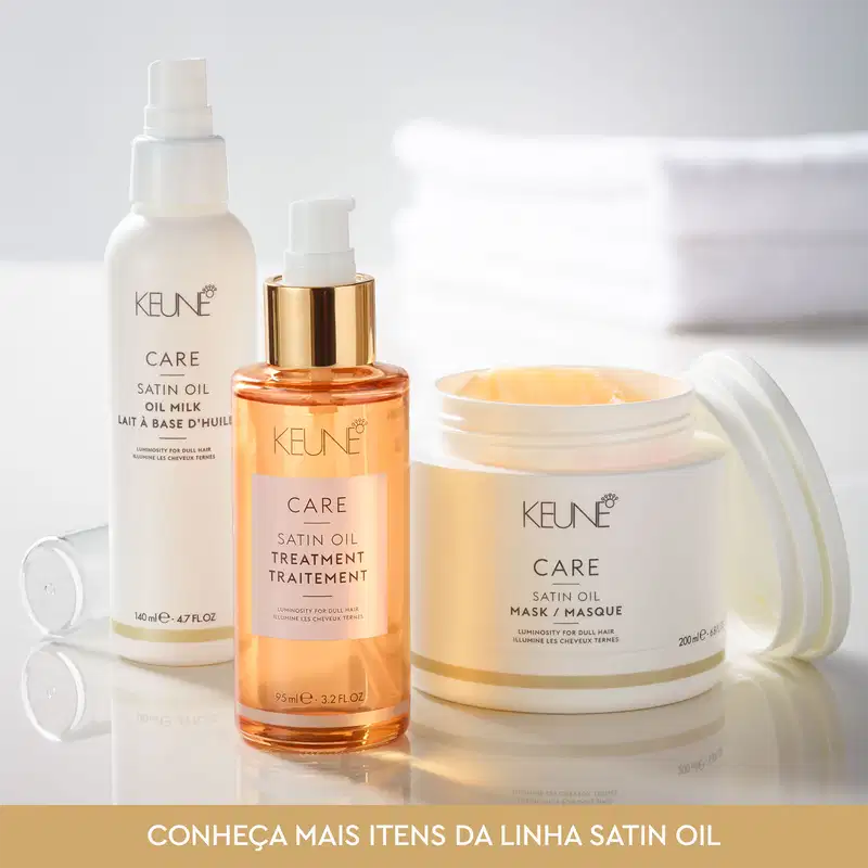 Produtos da linha Satin Oil da Keune, incluindo óleo capilar, tratamento e máscara, em embalagens brancas e douradas com rótulos destacados.
