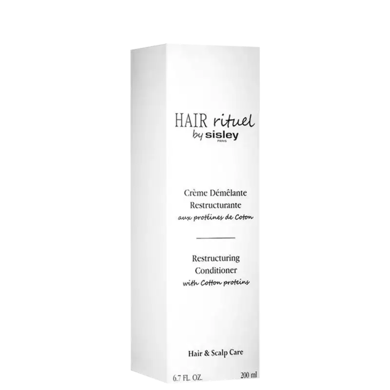Embalagem branca retangular com texto "HAIR rituel by sisley" em preto. Rótulo com título "Crème Démélante Restructurante" e informações sobre o produto em francês e inglês. Embalagem de item de perfumaria para cuidados com o cabelo.