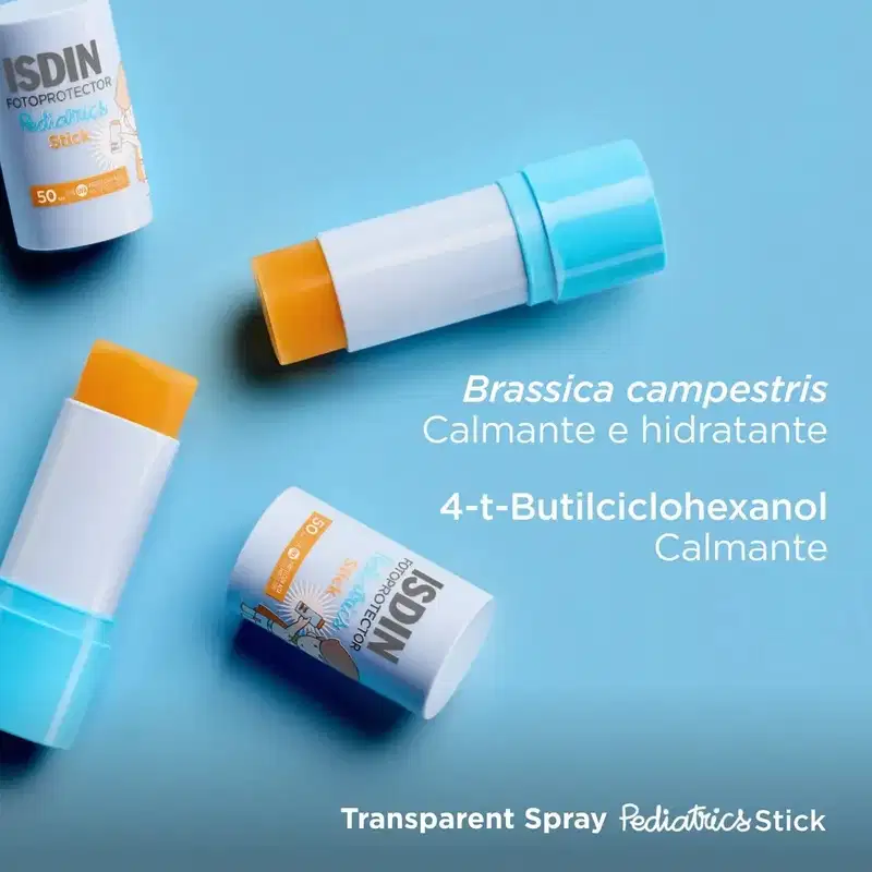 Produtos de proteção solar ISDIN Pediatrics dispostos em superfície azul claro: frasco spray, stick e embalagem cilíndrica com detalhes em branco e laranja, acompanhados de texto sobre ingredientes Brassica campestris e 4-t-Butilciclohexanol.