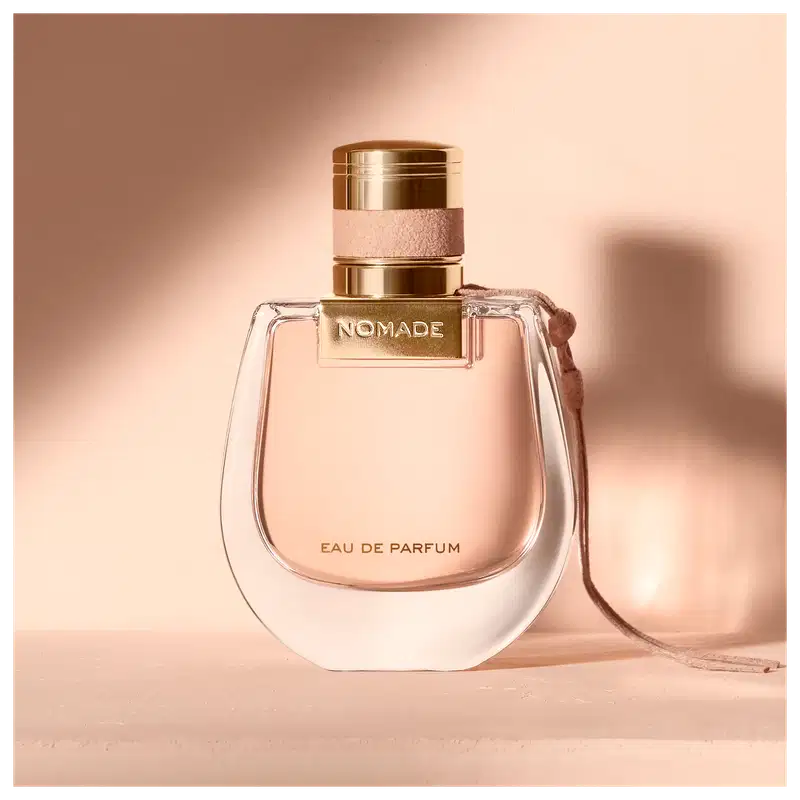 Perfume em um ambiente rosado, com uma luz sobre o frasco projetando uma sombra na parede.