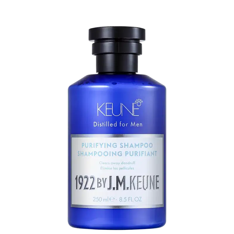 Shampoo em um frasco é azul translúcido, permitindo ver o líquido de cor azul vibrante dentro. A embalagem tem uma tampa preta e apresenta o nome da marca Keune, o nome da linha Distilled for Men e a descrição "Purifying Shampoo" em letras brancas.