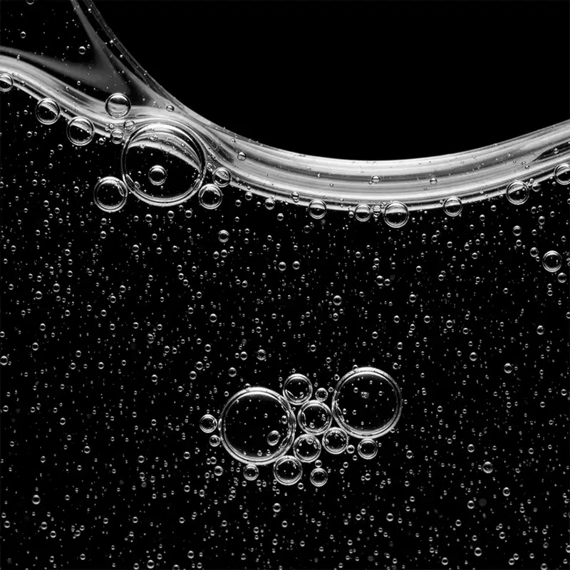 A imagem mostra uma textura de bolhas e gotas de água transparentes em um fundo escuro. A textura é fluida, brilhante e com uma aparência líquida, com diferentes tamanhos de bolhas e gotas dispersas uniformemente.