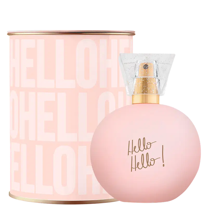 Perfume em embalagem redonda de vidro rosa claro com tampa dourada. Lata cilíndrica rosa com texto "Hello Hello!" em letras marrons. As cores predominantes são rosa claro, branco e dourado.