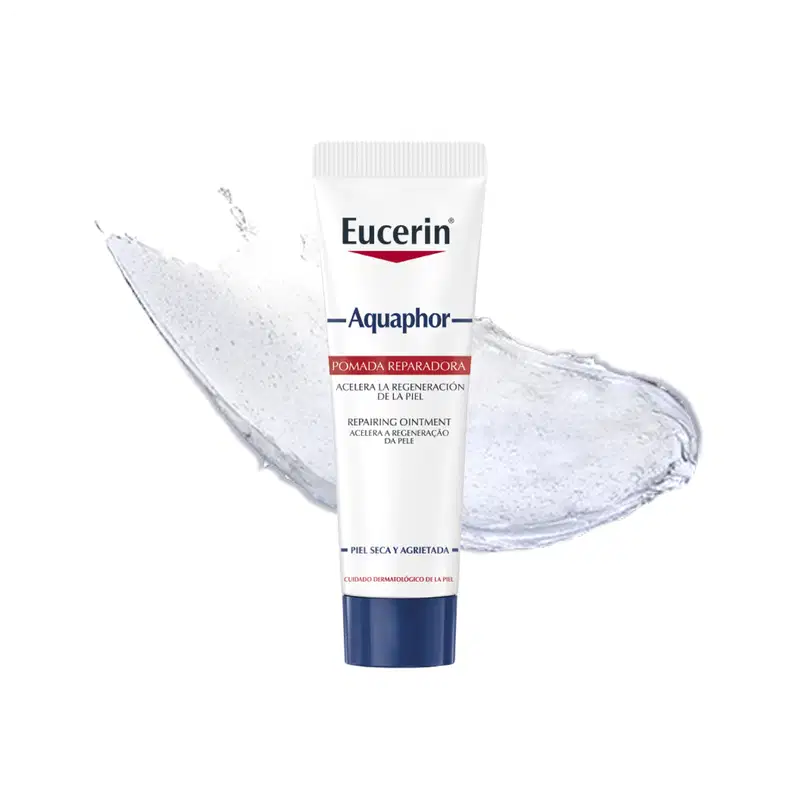 Tubo branco com logotipo da marca Eucerin contendo pomada reparadora com textura cremosa e brilhante, sobre fundo com respingos de água.