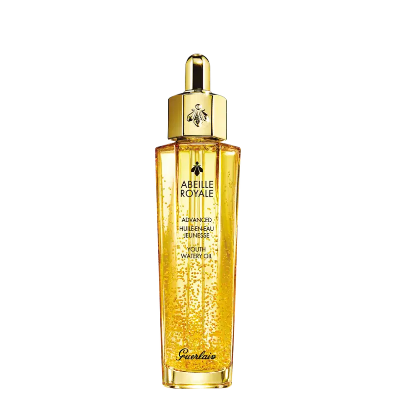 A imagem mostra o frasco do óleo hidratante Abeille Royale da Guerlain. É um frasco de vidro transparente contendo um líquido dourado brilhante, tem um formato cilíndrico alongado com uma tampa dourada na parte superior, com uma abelha estampada.