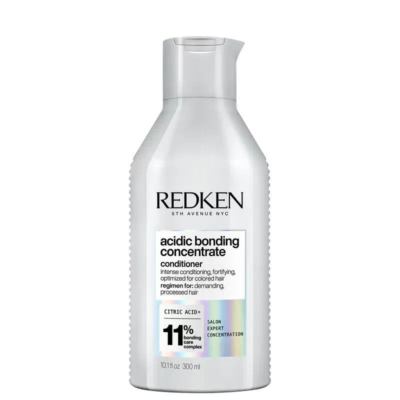 Frasco branco com rótulo da marca Redken. O rótulo apresenta o nome "Acidic Bonding Concentrate" e informações sobre o produto, como "intense conditioning, fortifying, optimized for colored hair". O frasco possui um design cilíndrico com tampa.